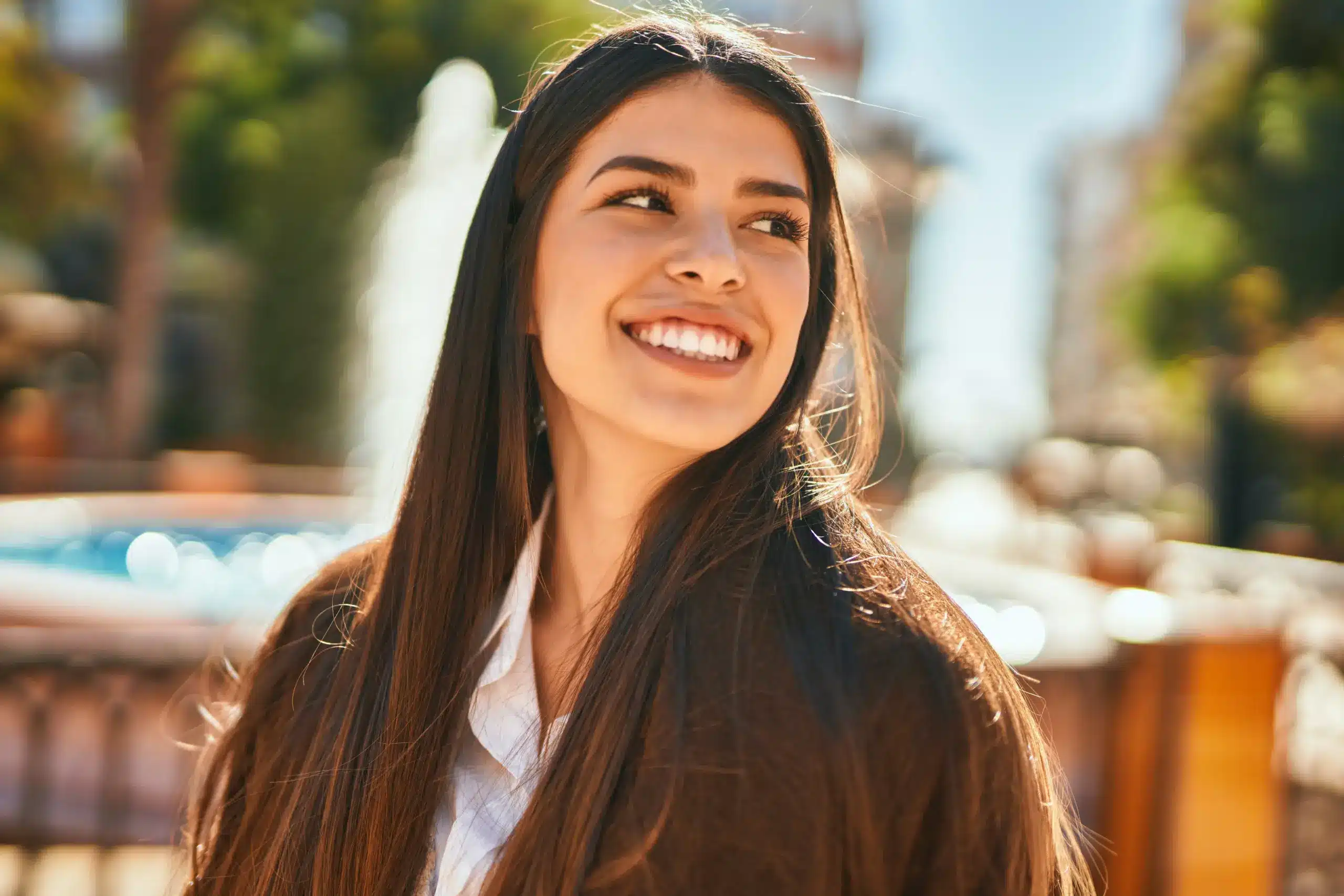 Confident woman smiling outdoors with a radiant, healthy smile after Bridges and Crown treatment