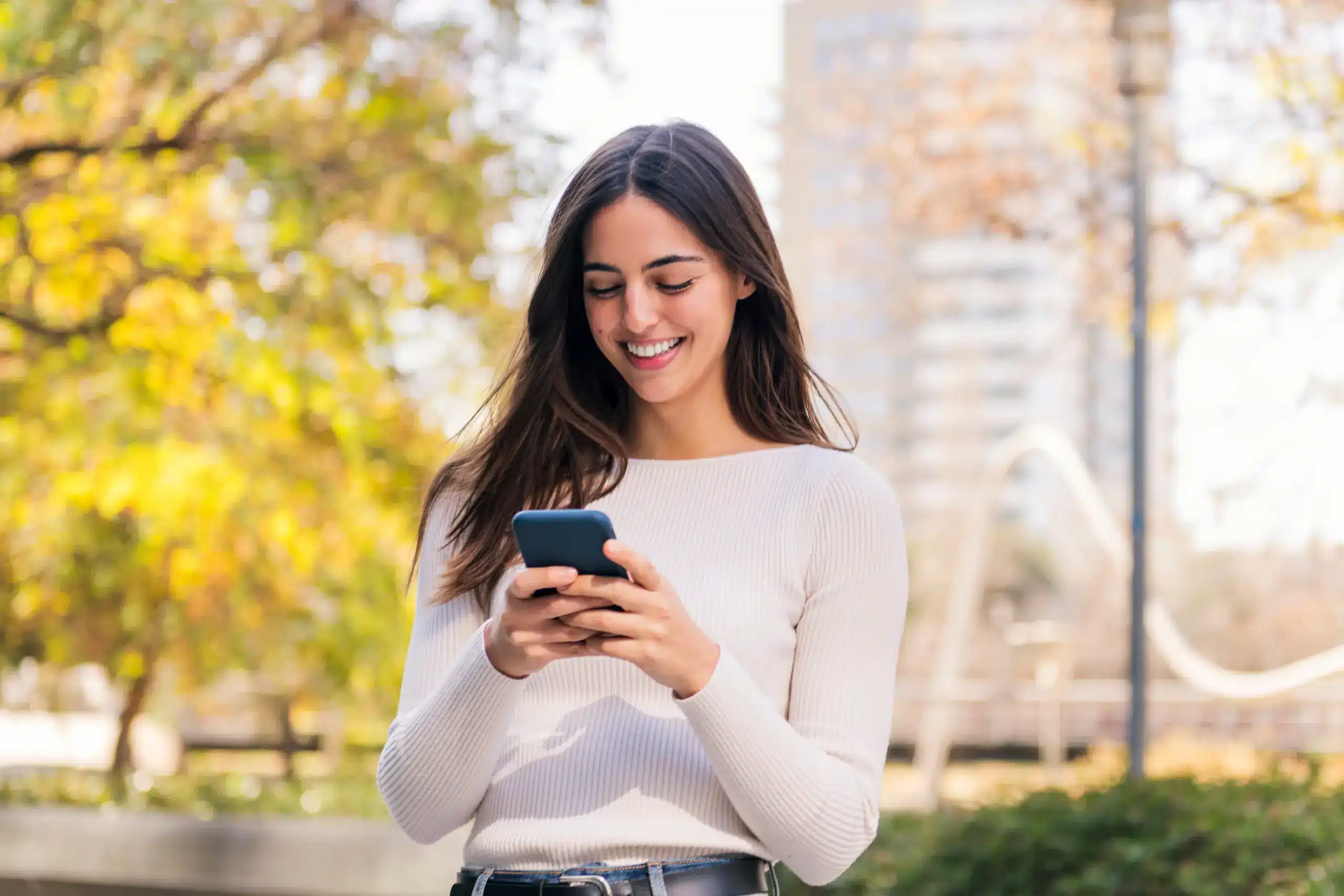 Young woman checking her phone outdoors, symbolizing simple scheduling with a Chambersburg, PA dentist